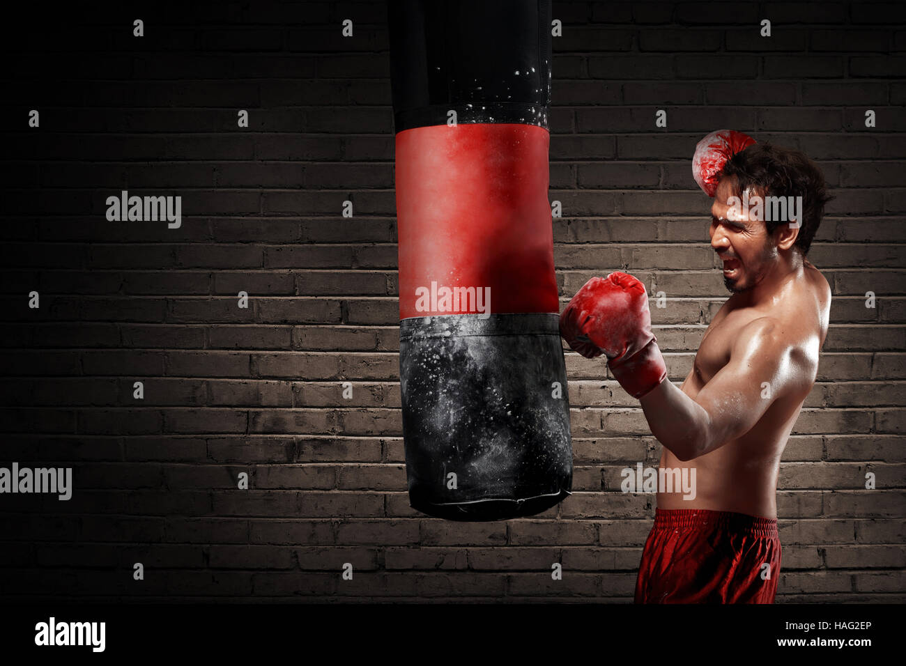 Young boxer training with punching the bag over wall background Stock