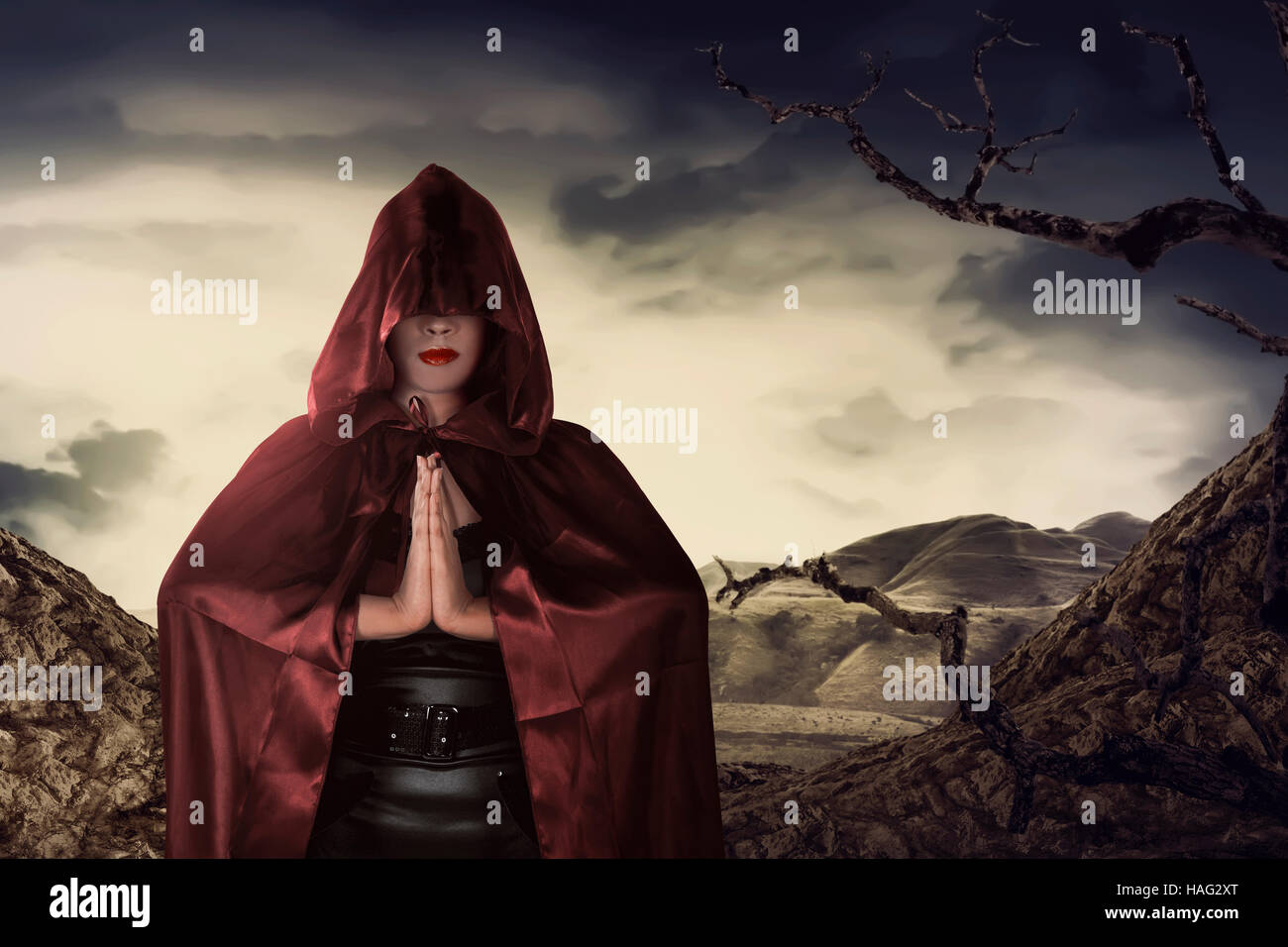 Beautiful asian witch woman with red cloak praying in hill Stock Photo
