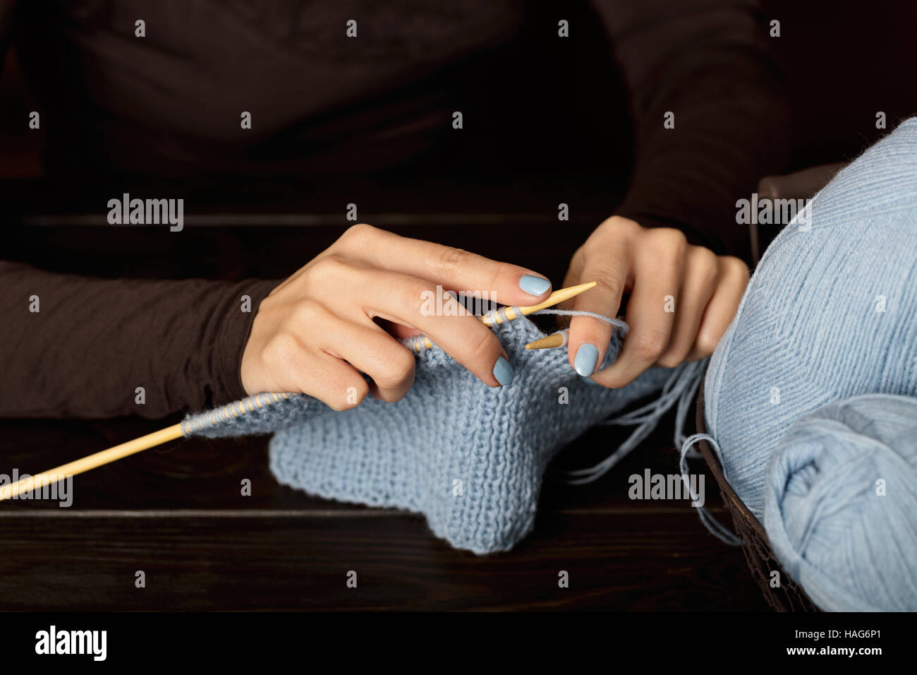 Female hands knitting from light blue yarn. Stock Photo