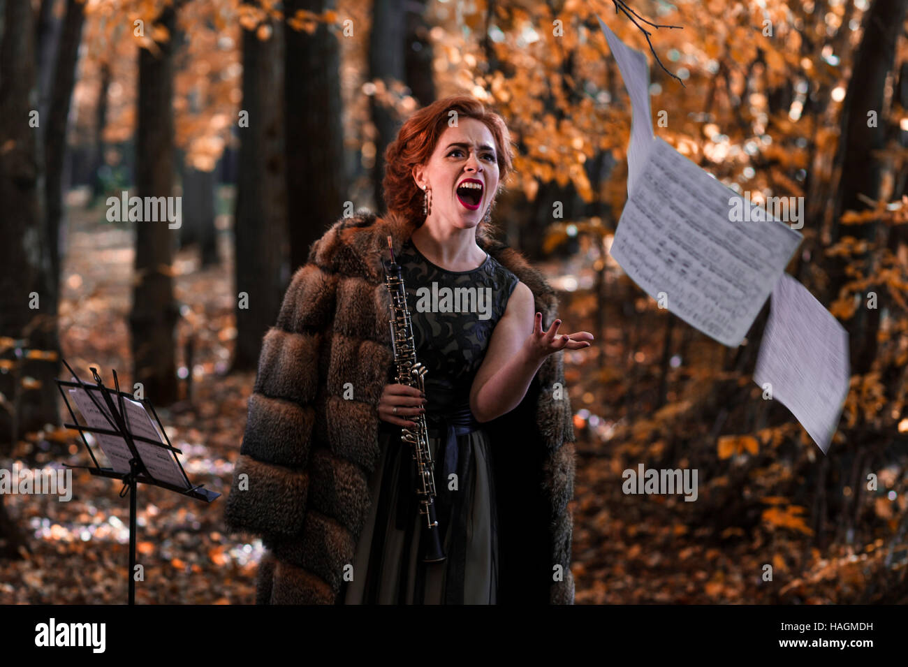 Young emotional woman throwing away the musical sheets and holding an oboe in hand Stock Photo