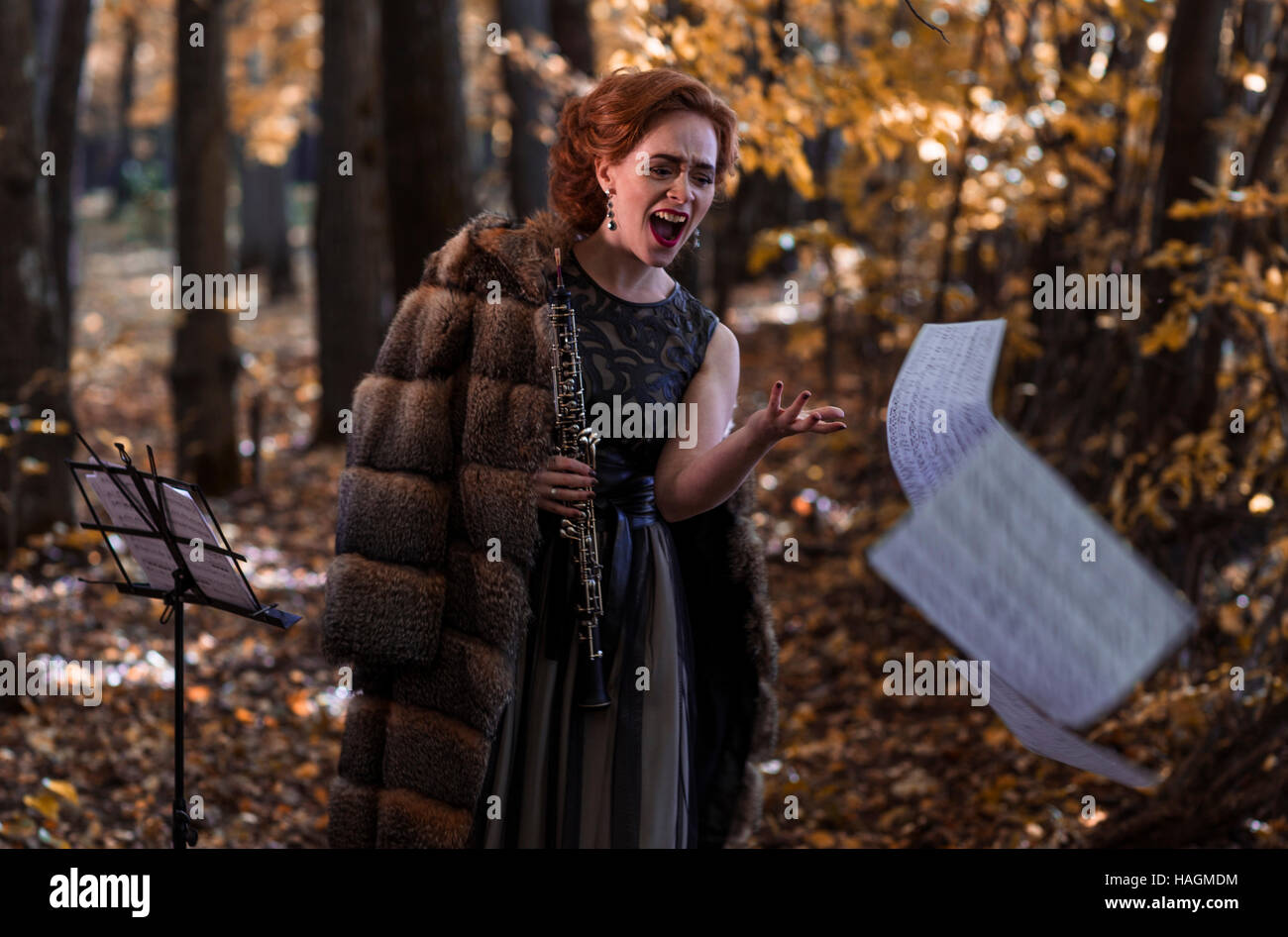 Young emotional woman throwing away the musical sheets and holding an oboe in hand Stock Photo