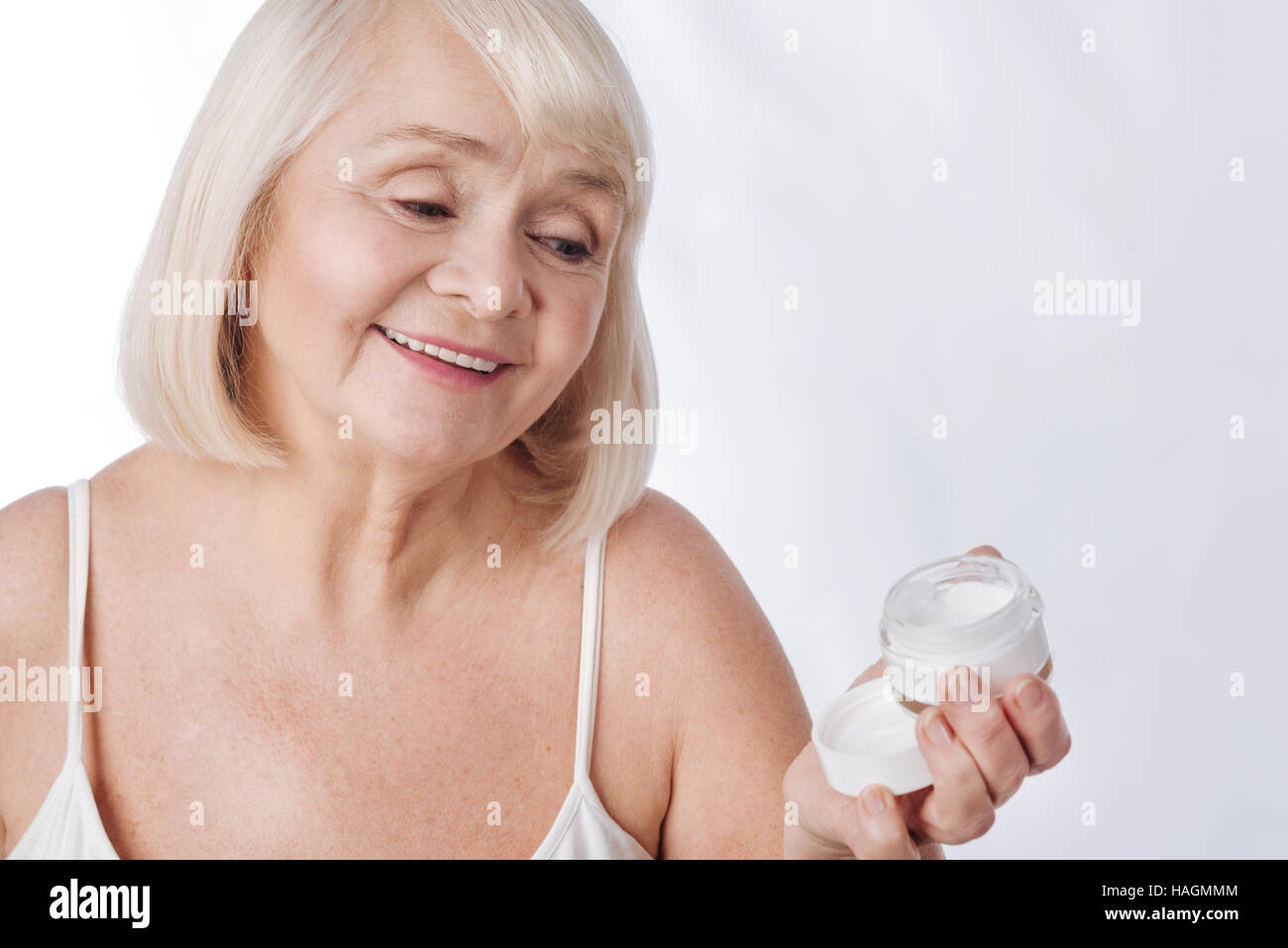 Happy aged woman using moisture cream Stock Photo