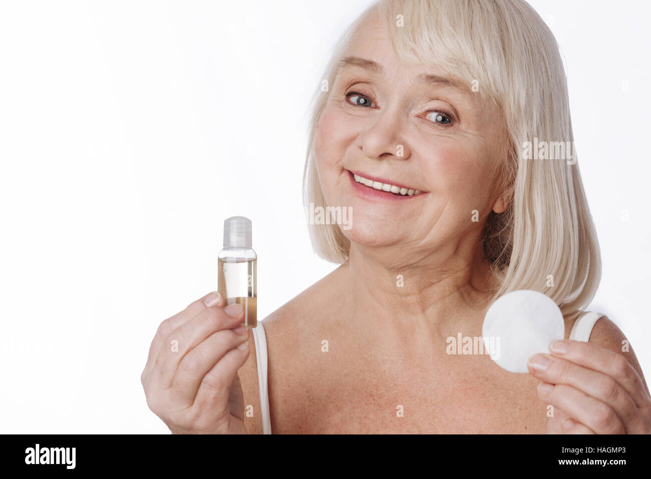 Elated senior woman holding lotion and a cotton pad Stock Photo