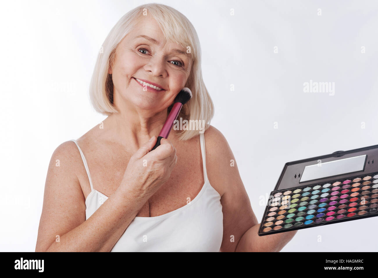 Joyful retired woman holding an eyeshadow palette Stock Photo