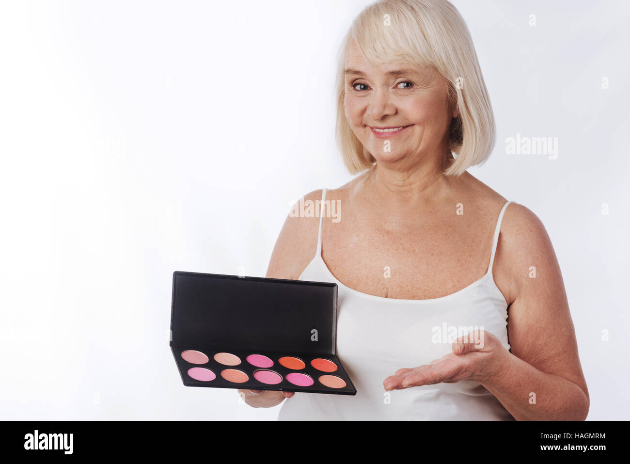 Happy elderly woman using decorative cosmetics Stock Photo
