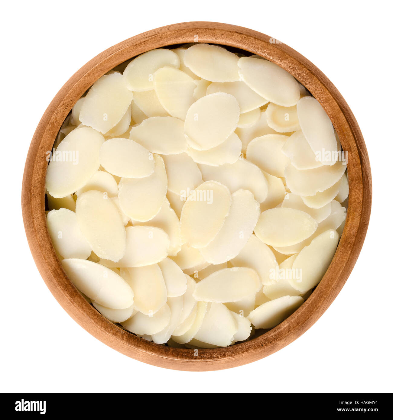 Sliced blanched almonds in wooden bowl. The light yellow raw edible seeds of Prunus dulcis are not nuts, but botanically drupes. Stock Photo