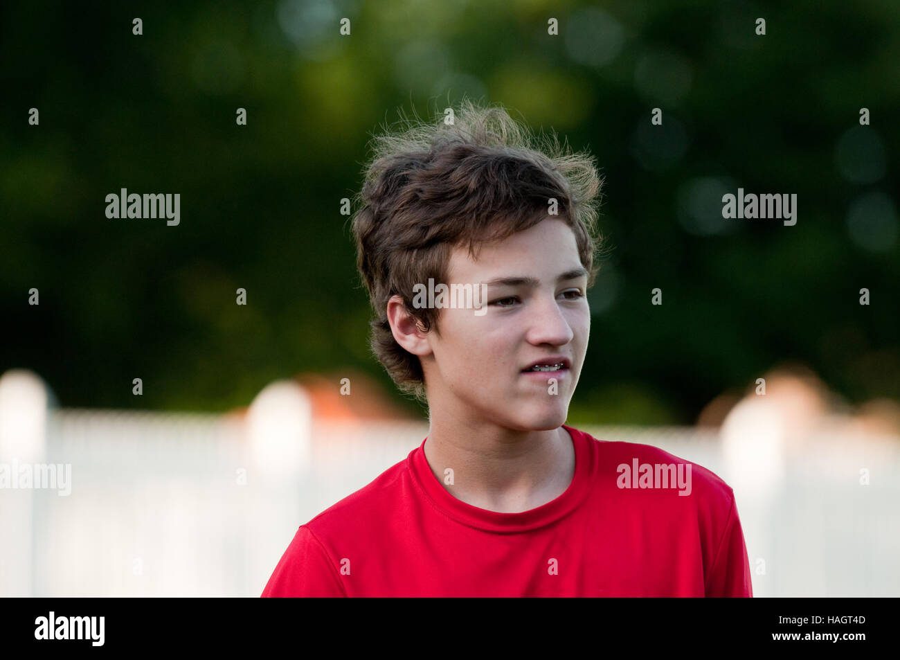 Cute teen boy outside with red shirt, braces, and messy hair Stock