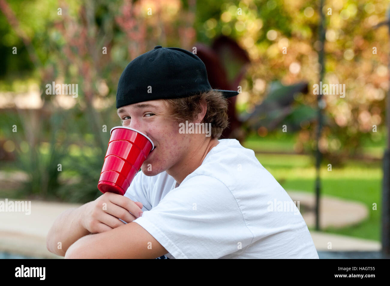 Teen boy outdoors with acne looking at camera with black backwards hat