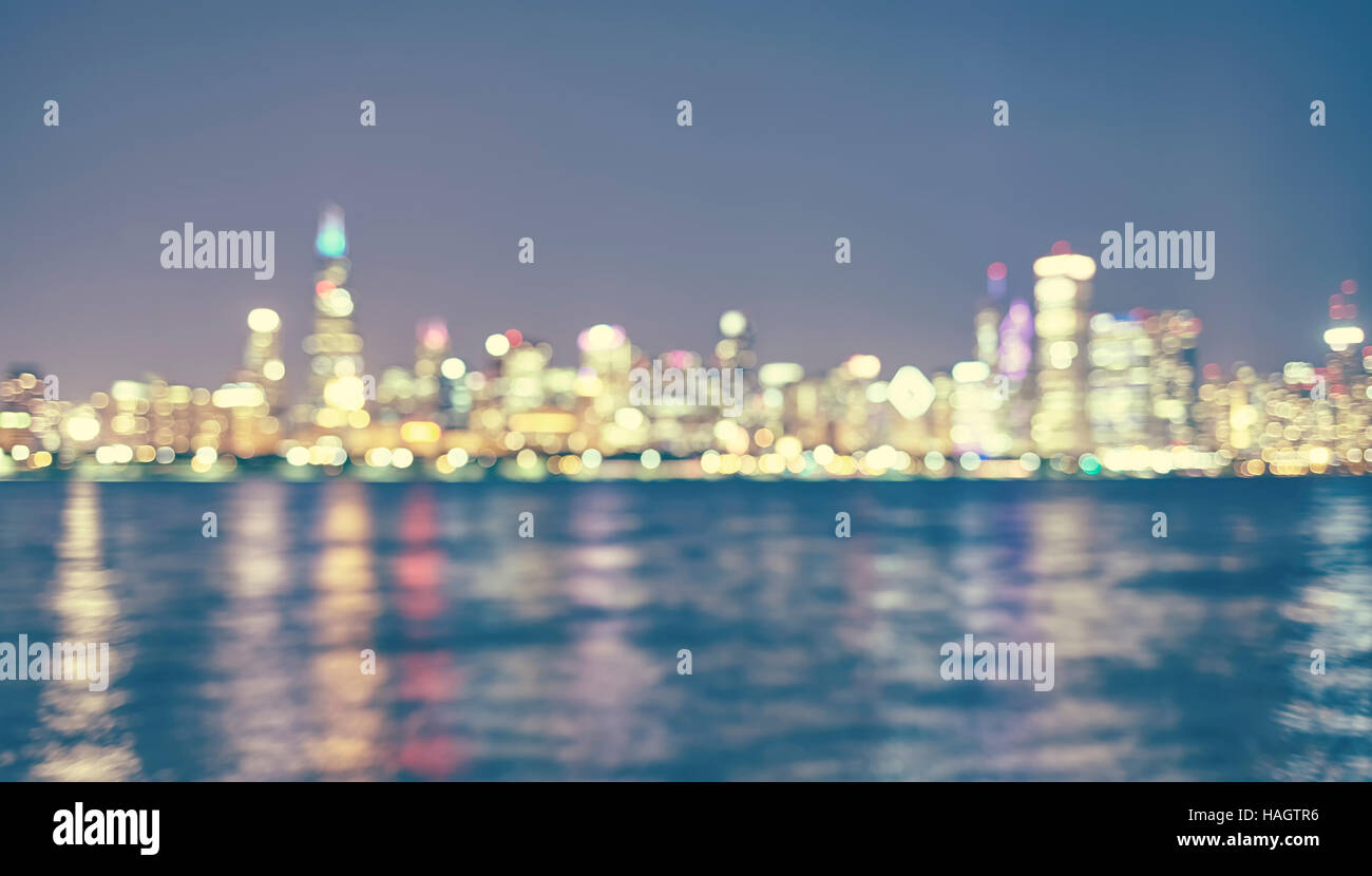 Vintage toned blurred Chicago city lights with reflection in Lake Michigan at night, urban abstract background. Stock Photo