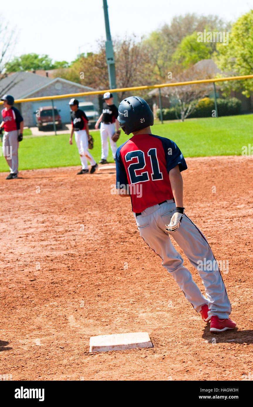 Teen baseball player rounding first base when running. Stock Photo