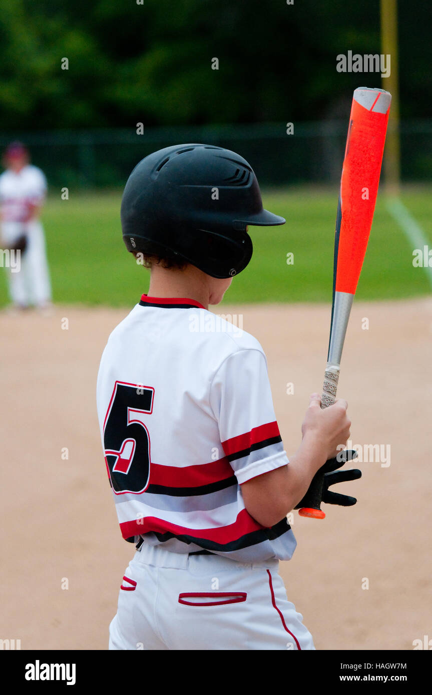 Rearview close-up of youth baseball player looking at bat. Stock Photo