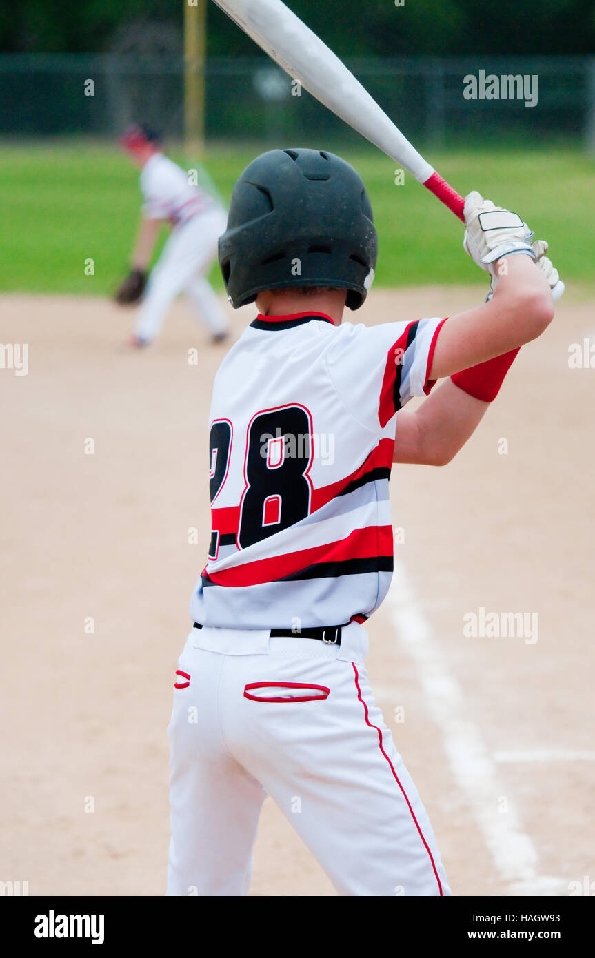 Youth baseball kid holding bat at home plate. Stock Photo