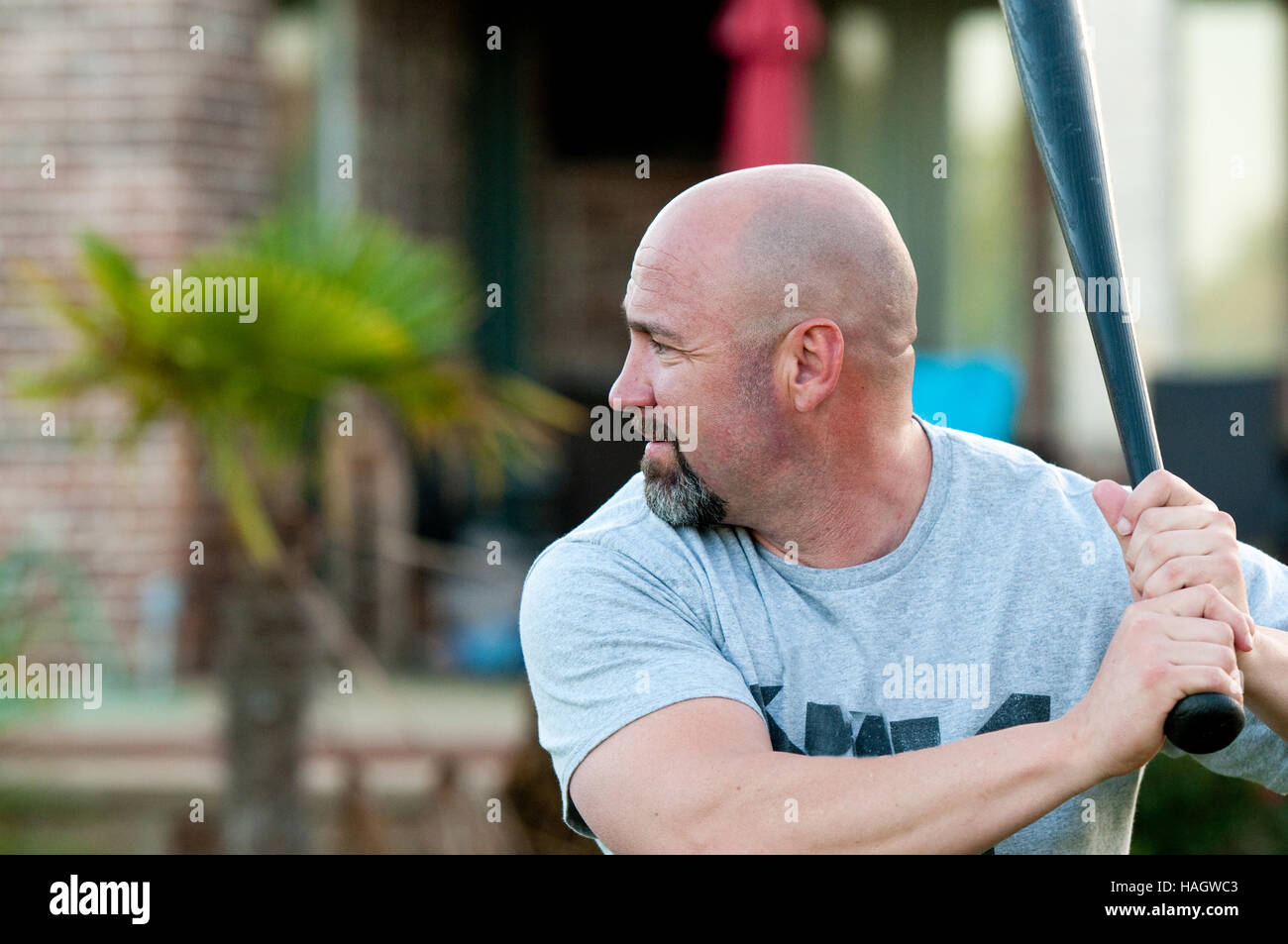 Middle-aged bald man playing holding baseball bat ready to swing. Stock Photo