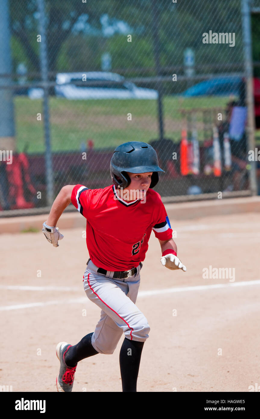 Youth teenage baseball kid running to first base. Stock Photo