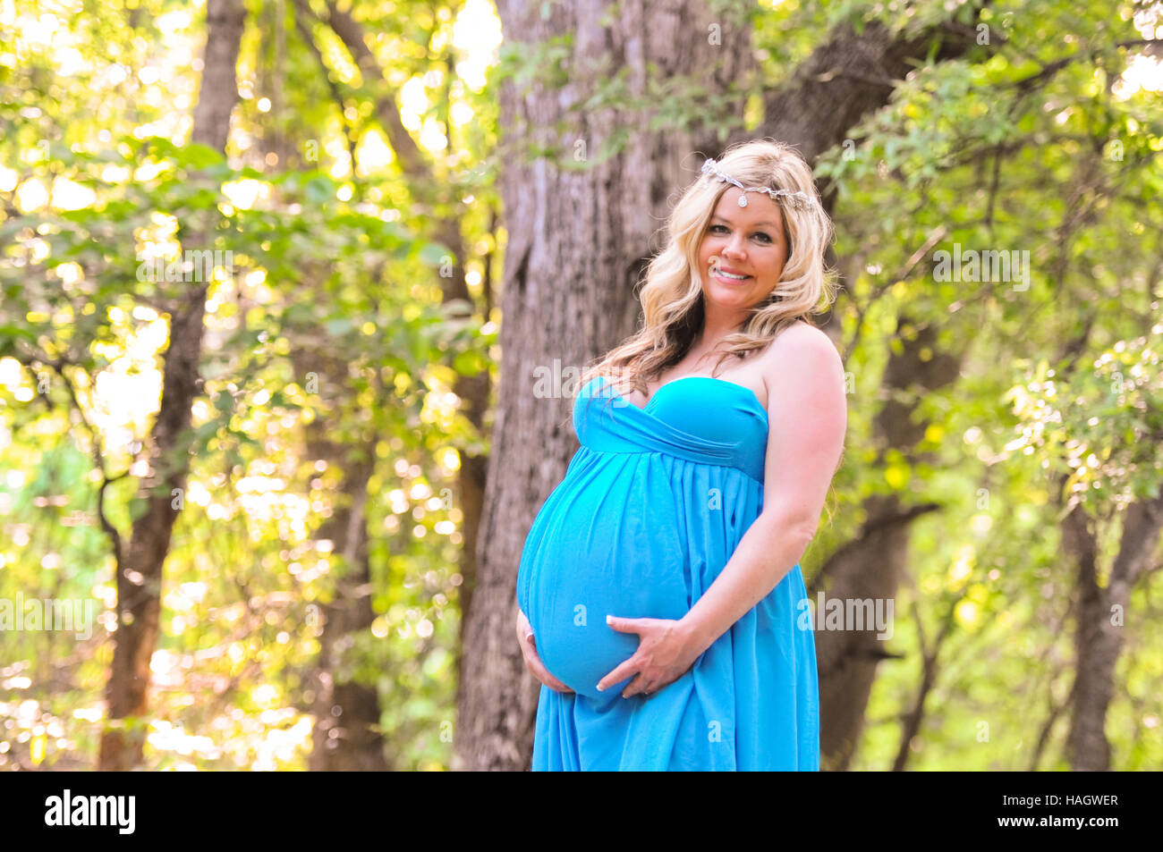Maternity portrait of stunning blonde female standing in the woods. Stock Photo