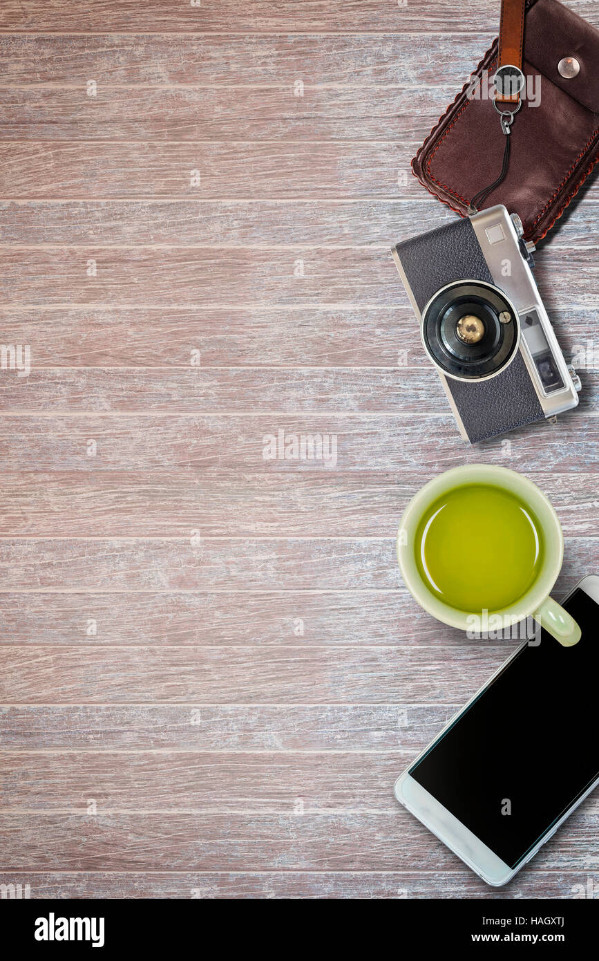vintage camera , leather bag ,smartphone and cup of tea on wooden background. Stock Photo