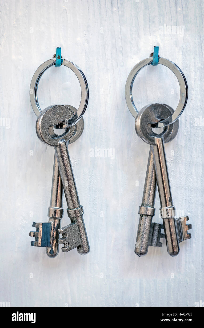 bunch of silver door keys on ring hang on white wooden wall background ...