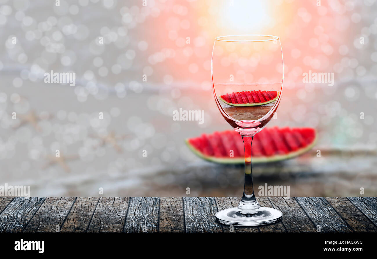 slices of the watermelon reflected in wine glass on wooden table under the sunlight Stock Photo