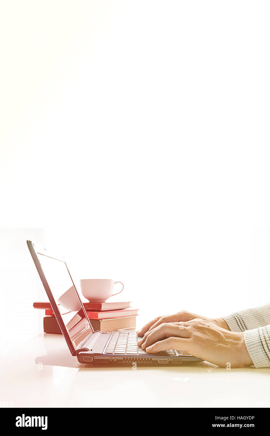 hands with laptop typing in warm light,bright white background. Stock Photo