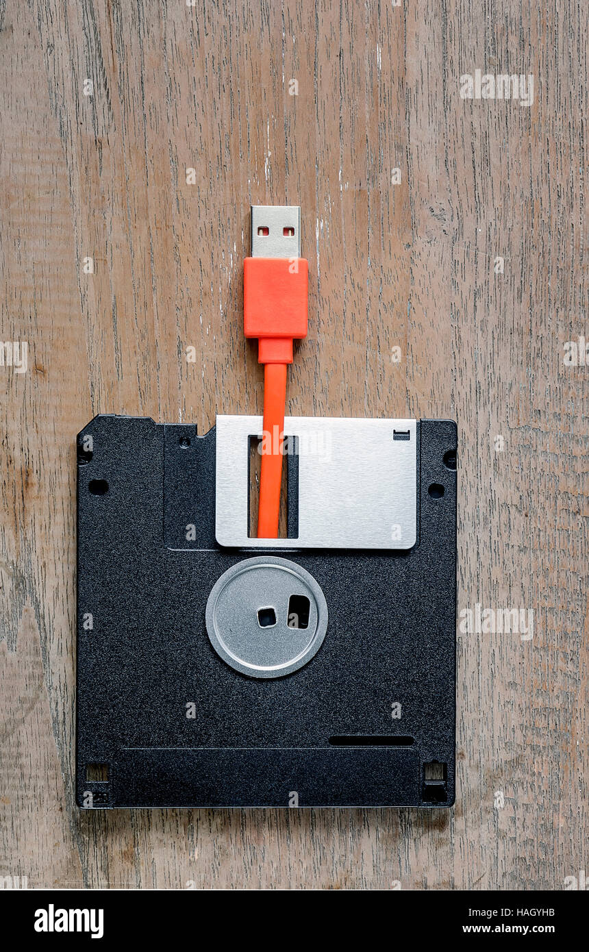 Used floppy diskettes with orange USB cable Plug on wooden background