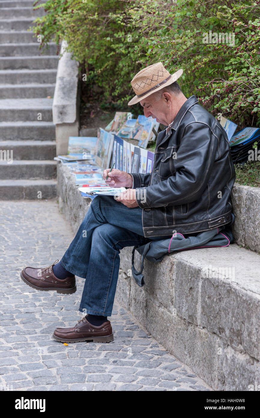 Male artist sat on a stone wall working, Split, Croatia. Stock Photo