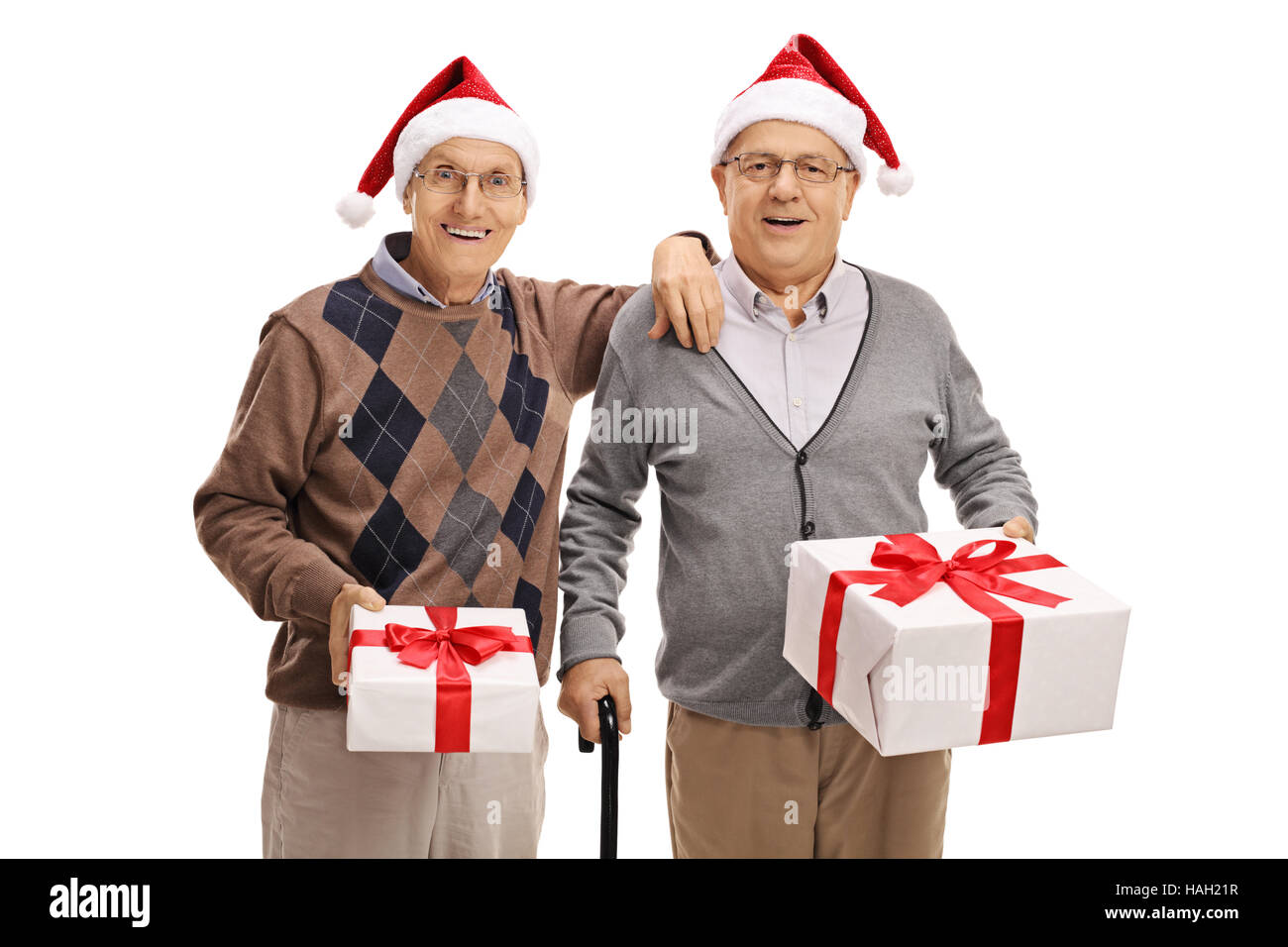 Two elderly men wearing santa hats and holding christmas presents isolated on white background Stock Photo