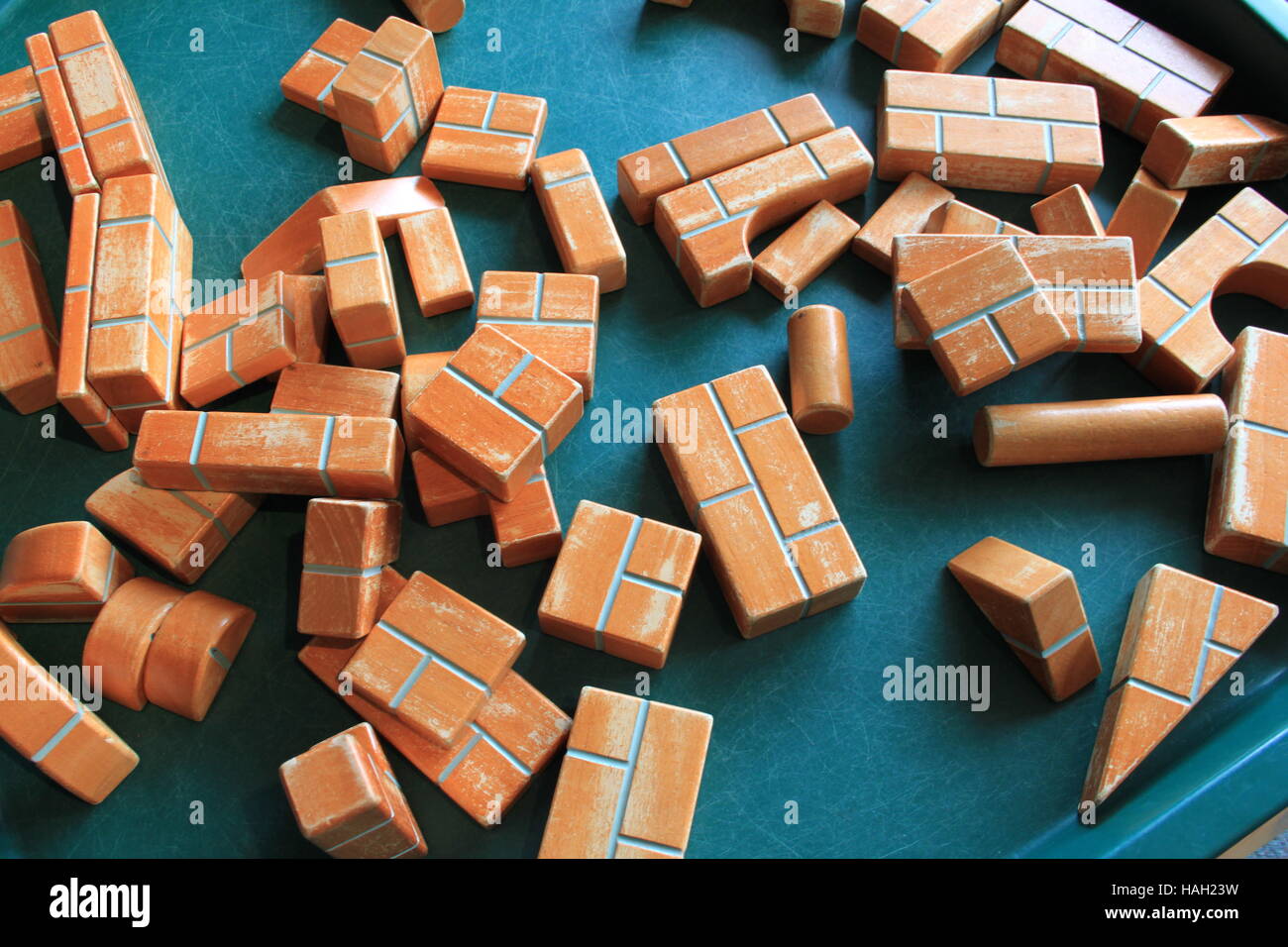 Randomly scattered traditional, toy, old fashioned, well used, wooden, building bricks on blue background. Stock Photo