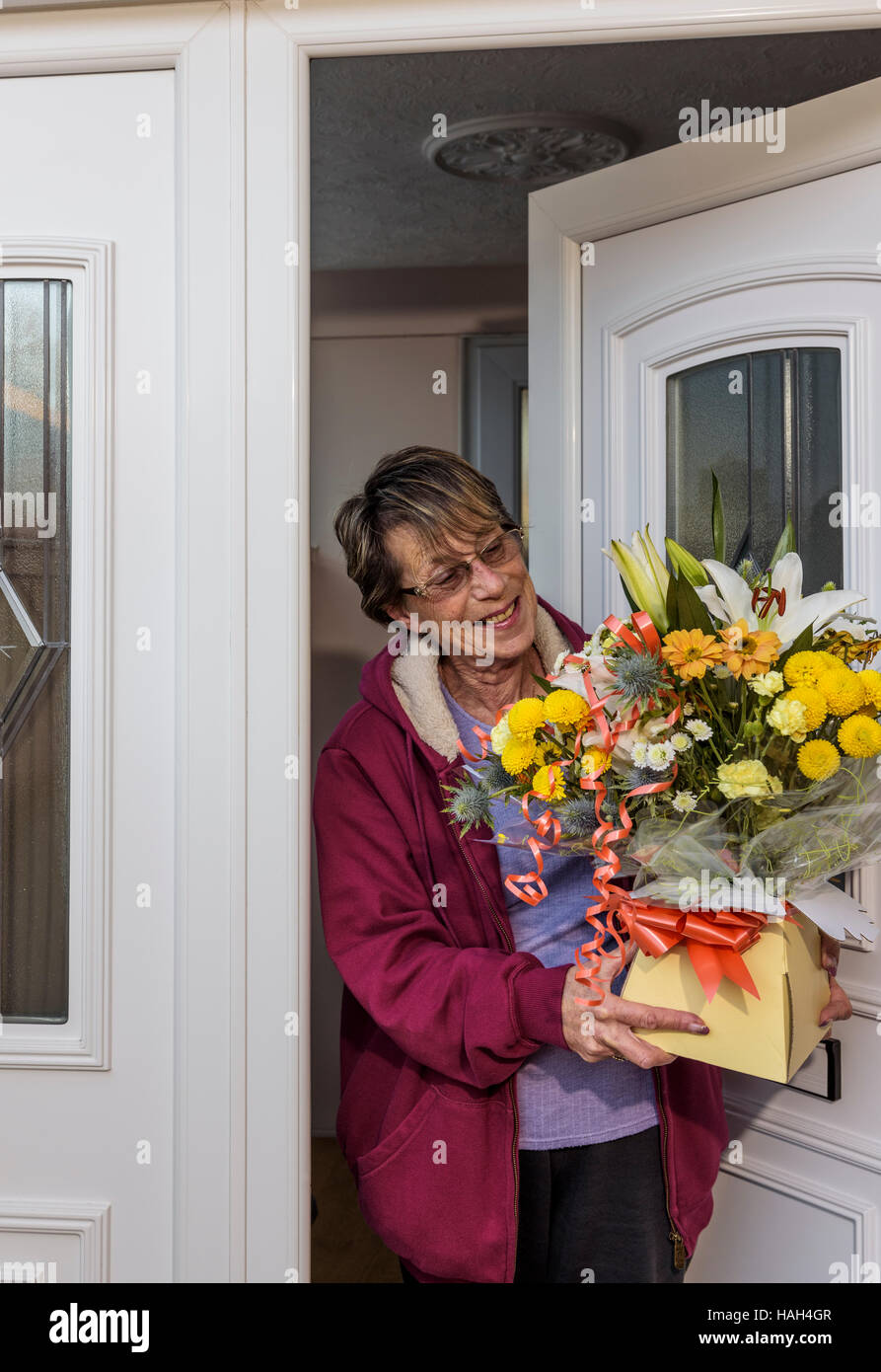 Senior lady accepting a flower delivery on mothers day or birthday. Stock Photo