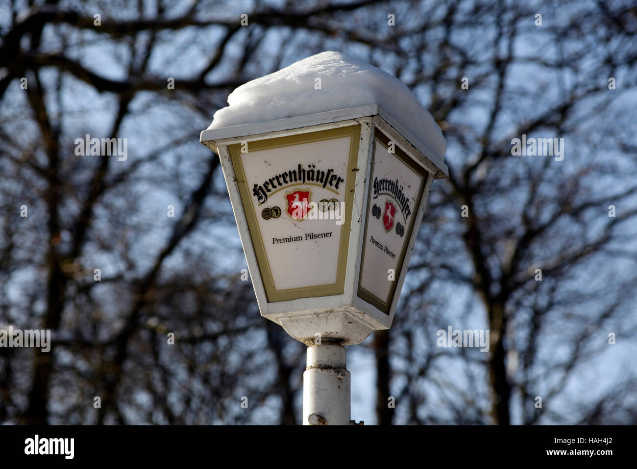 Lantern lamp covered with snow with publicity of Herrenhäuser Beer. Dornröschen Beer Garden, Hannover, Lower Saxony, Germany. Stock Photo