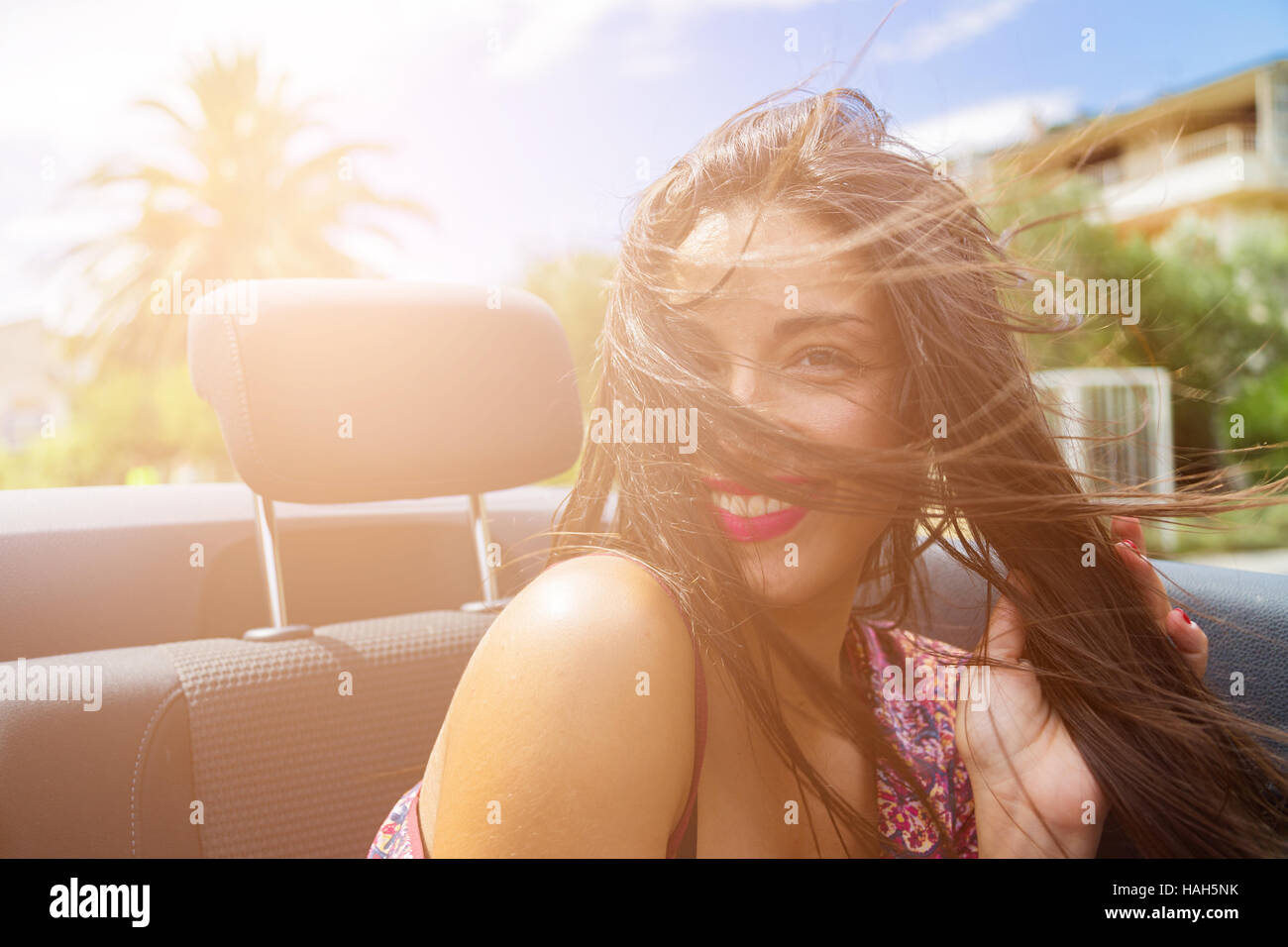 Happy brunette girl sitting and smiling in the back seat of convertible ...