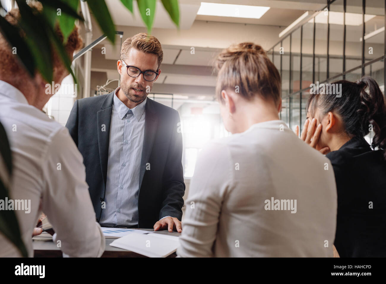 Businessman explaining new business strategy to colleagues. Group of business people having meeting in modern office. Stock Photo