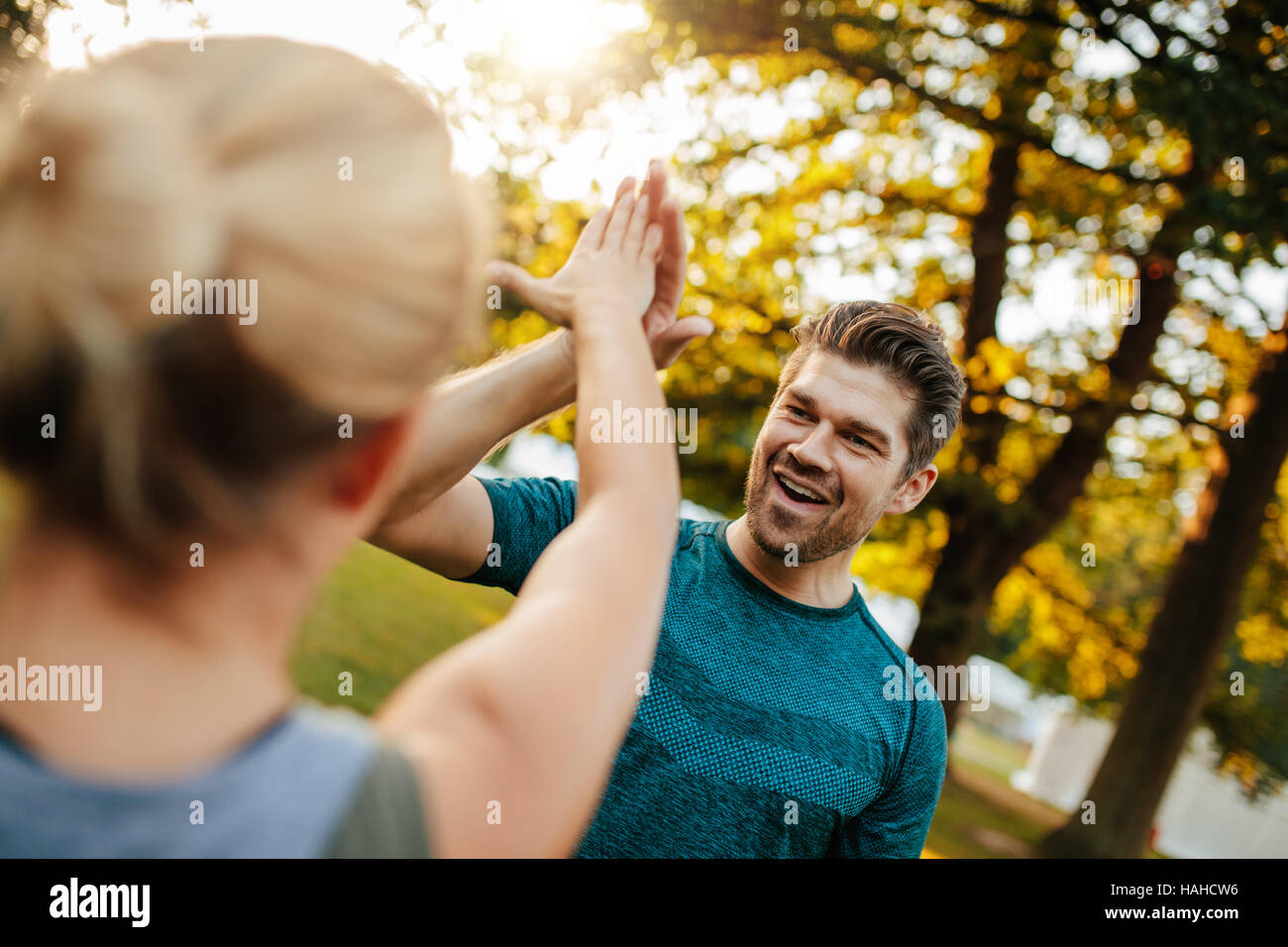 Shot of fit young man giving high five to woman. fitness couple in park giving high five. Stock Photo