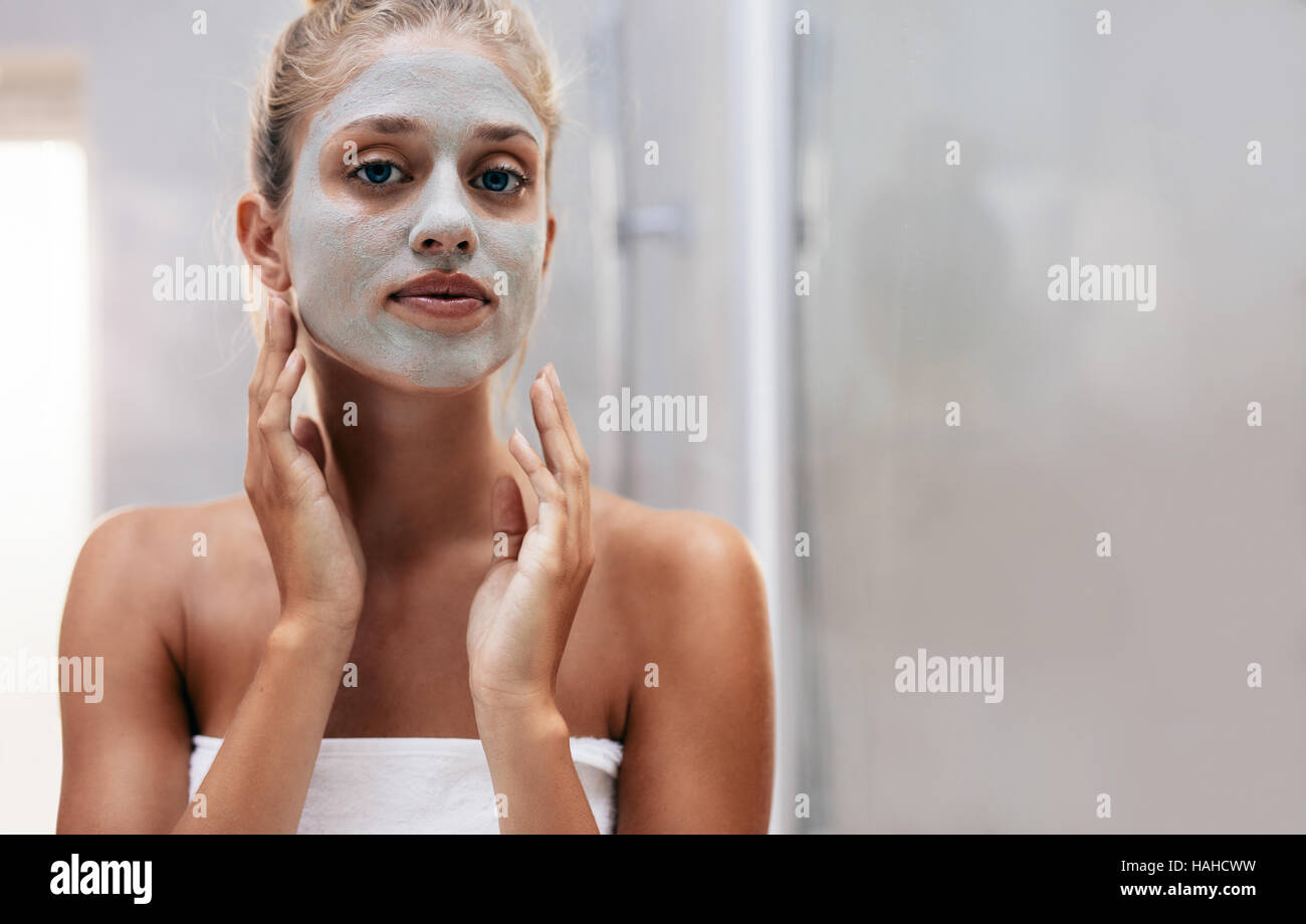 Close up shot of woman with facial mask in bathroom. Beautiful female doing beauty treatment after bath. Stock Photo