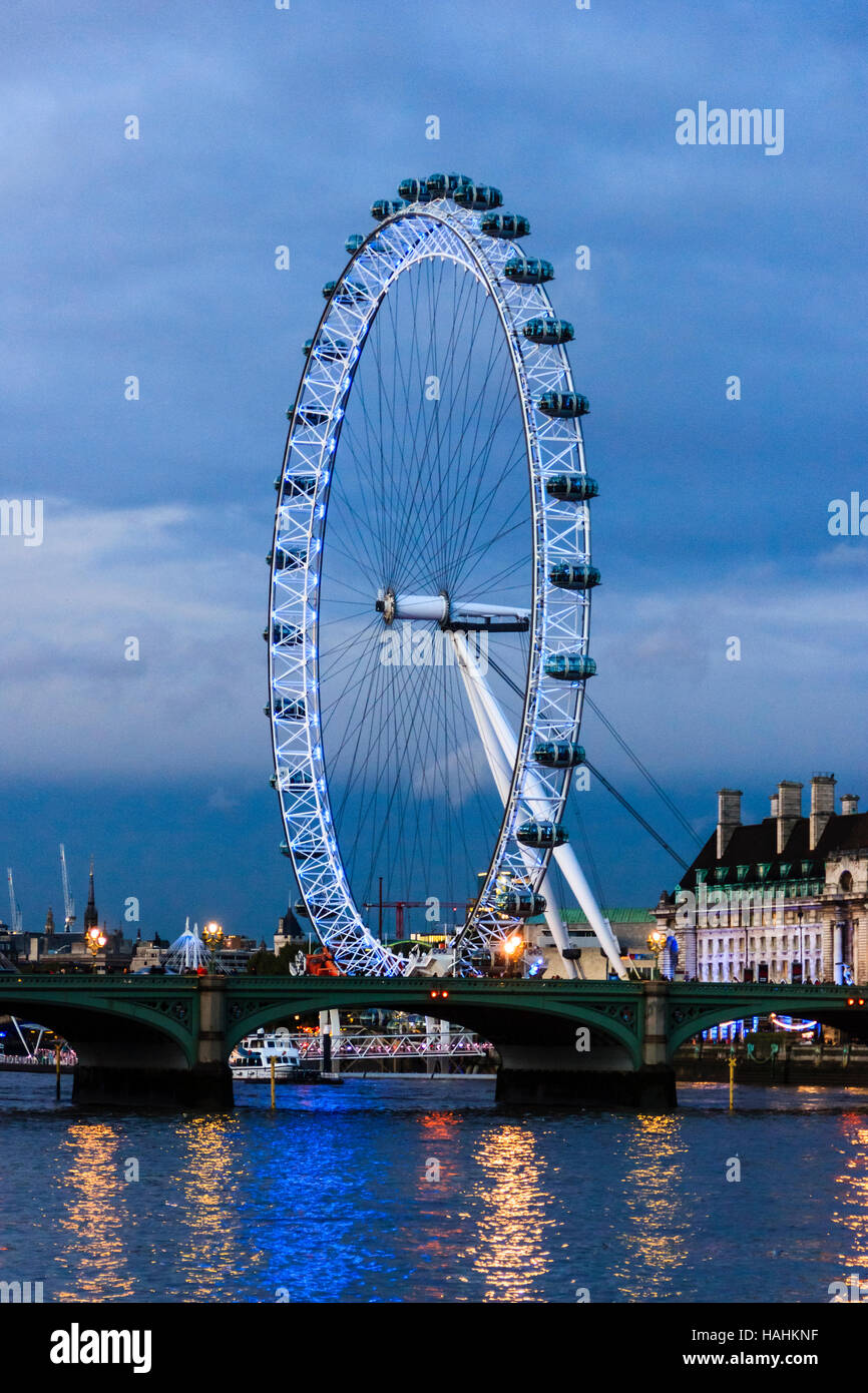 The London Eye lit up at night, seen from across the River Thames on the Victoria Embankment, London, UK Stock Photo