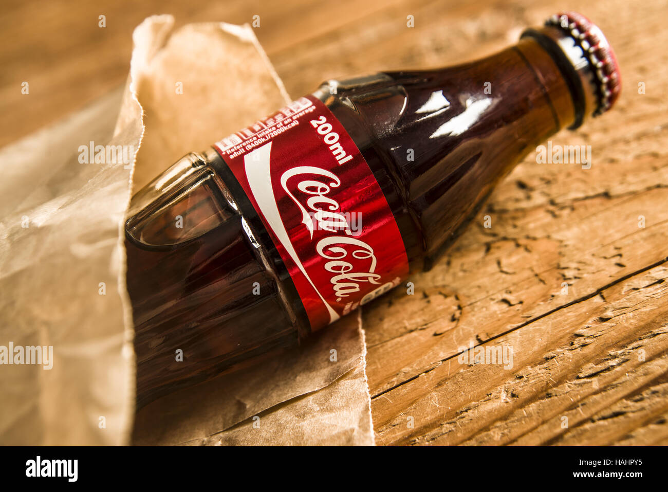 MOSCOW, RUSSIA - NOVEMBER 26, 2016 : Coca cola drinking in paper sack lie on wooden table background. natural brown Bag for fast food Stock Photo