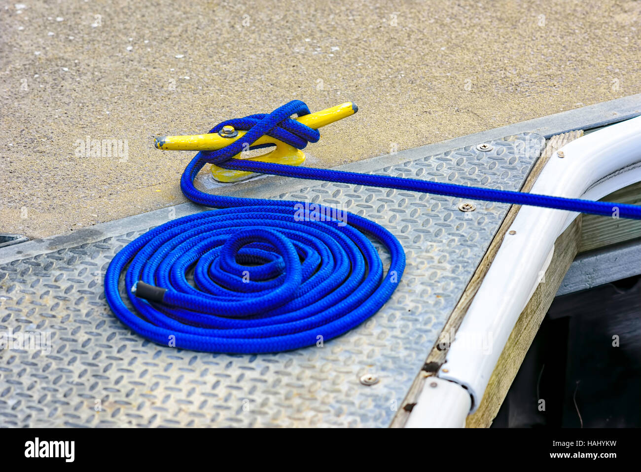 Blue mooring rope tied to yellow cleat Stock Photo