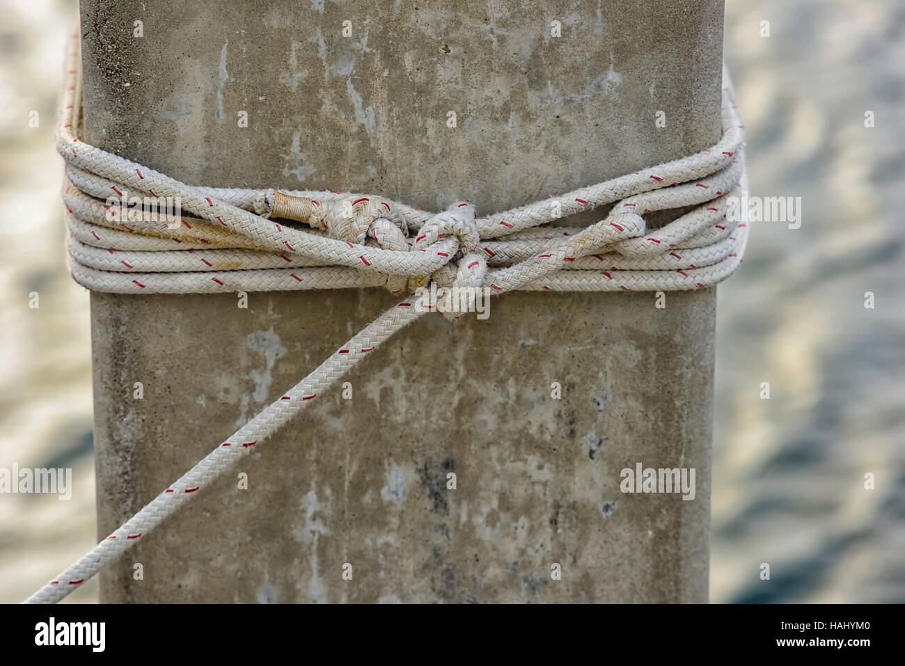 mooring rope tied off to concrete piling Stock Photo
