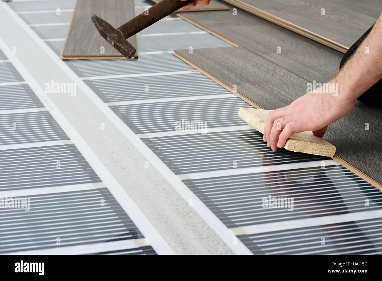 man installing laminate floor over infrared carbon heating system Stock Photo