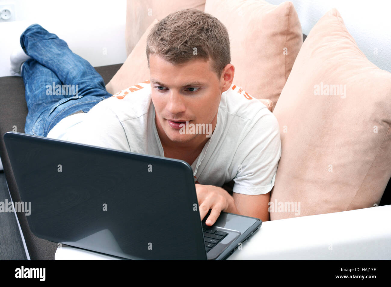 young man laying on sofa and using laptop Stock Photo Alamy