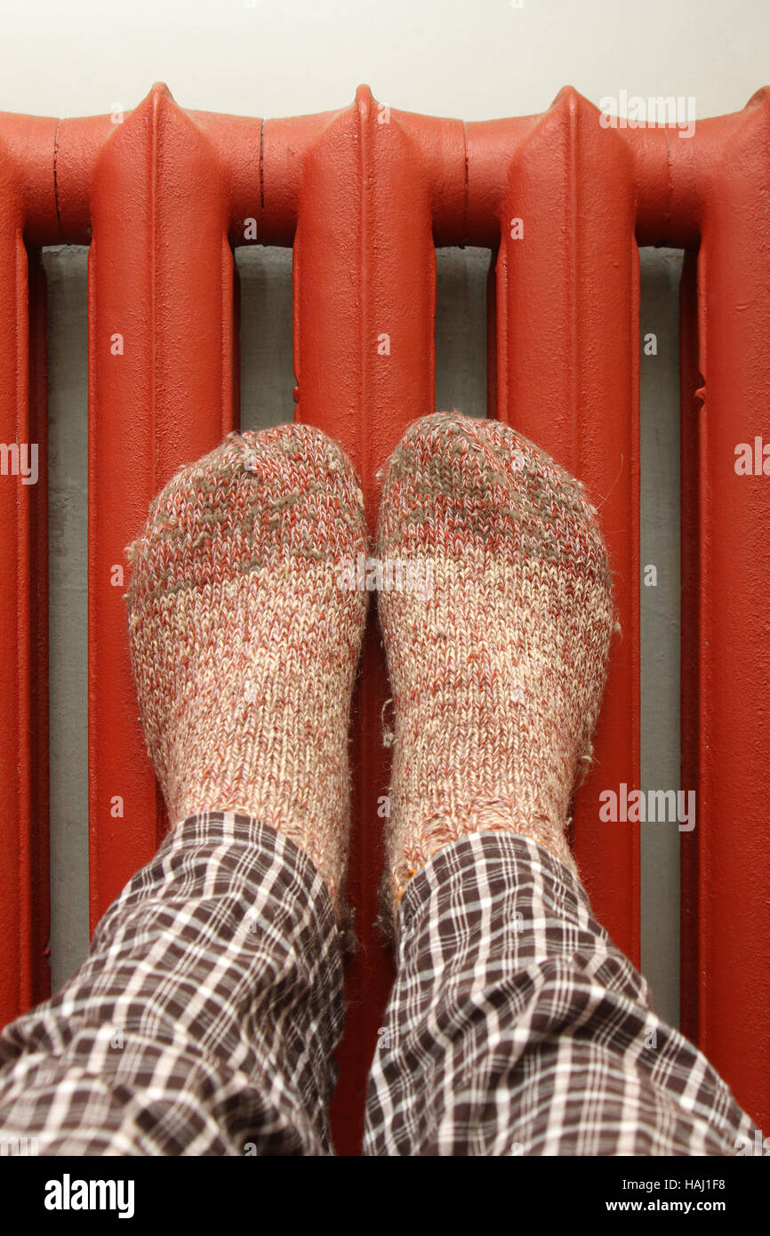 feet with wool socks warming on the radiator Stock Photo