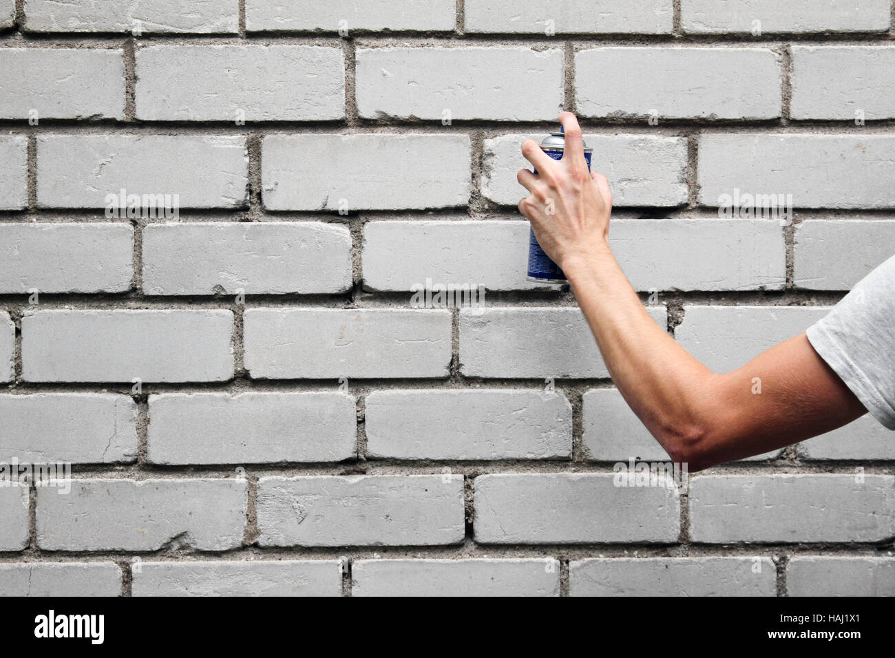 hand holding a graffiti spray can in front of a brick wall Stock Photo ...