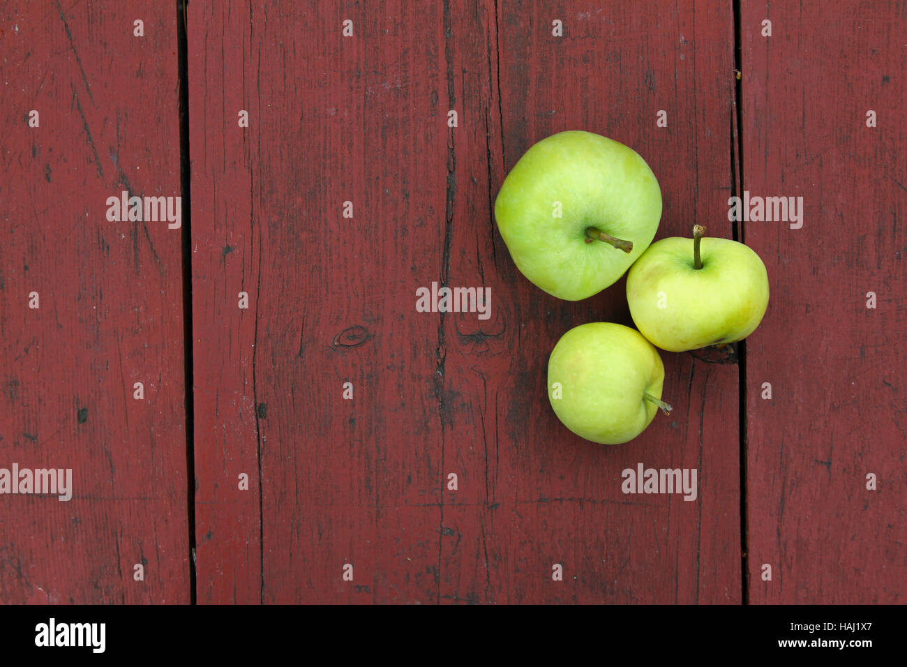 three green apples on red old wooden table Stock Photo