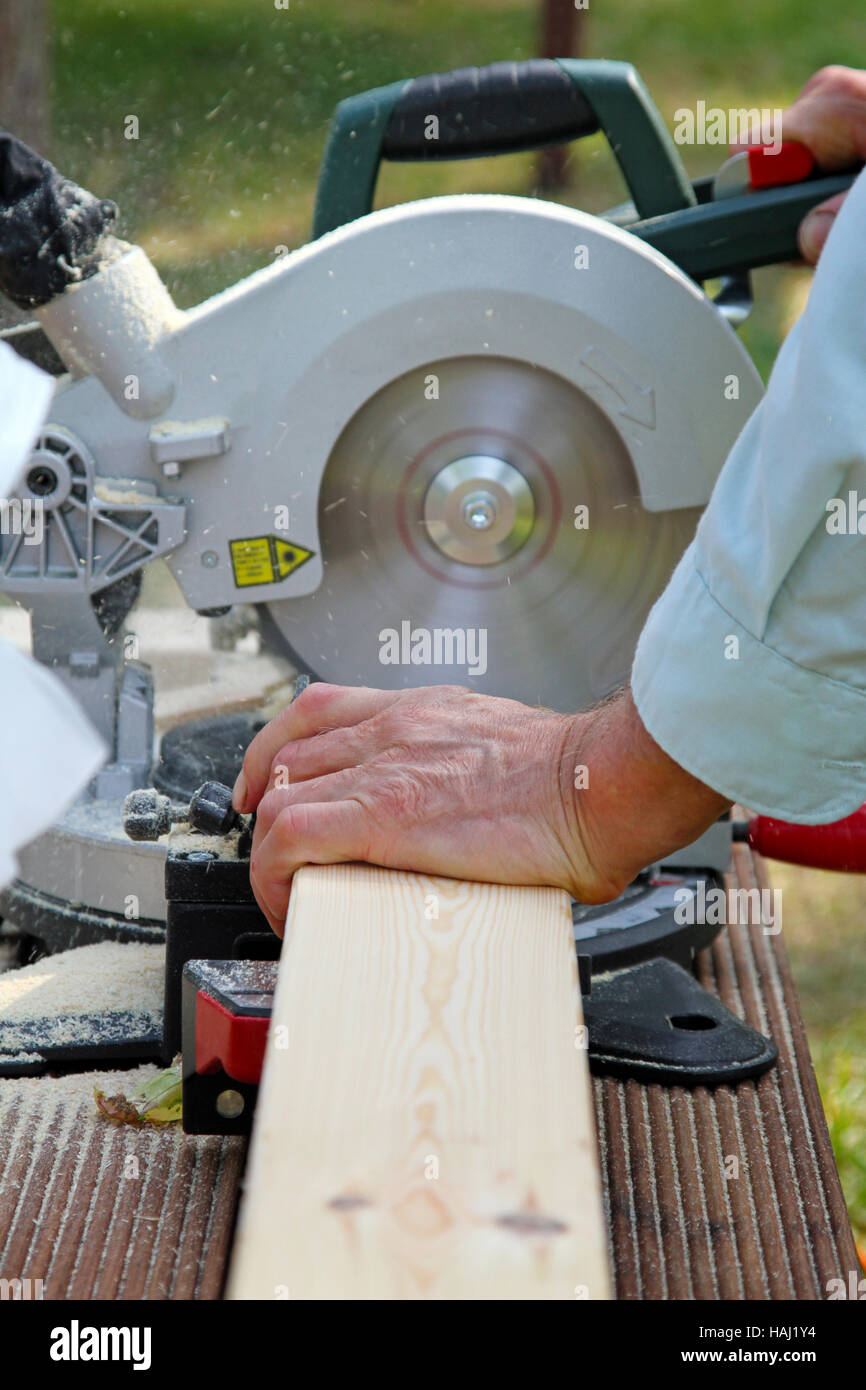 carpenter cutting wooden plank with circular saw Stock Photo