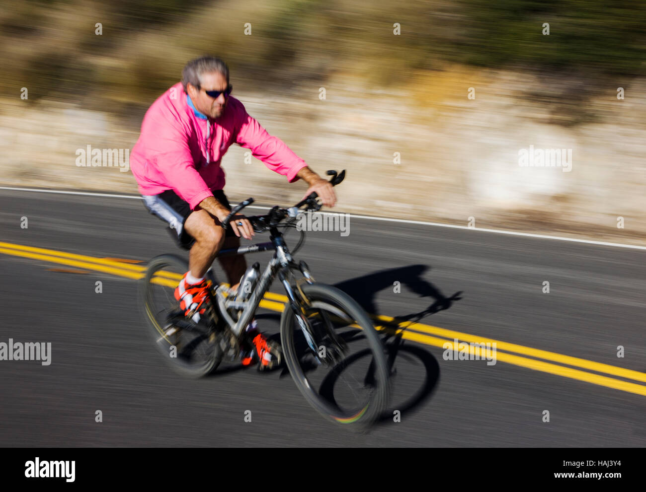 Man in a blur of motion riding a bike down a road near Rt. 1 and Malibu, California, USA Stock Photo