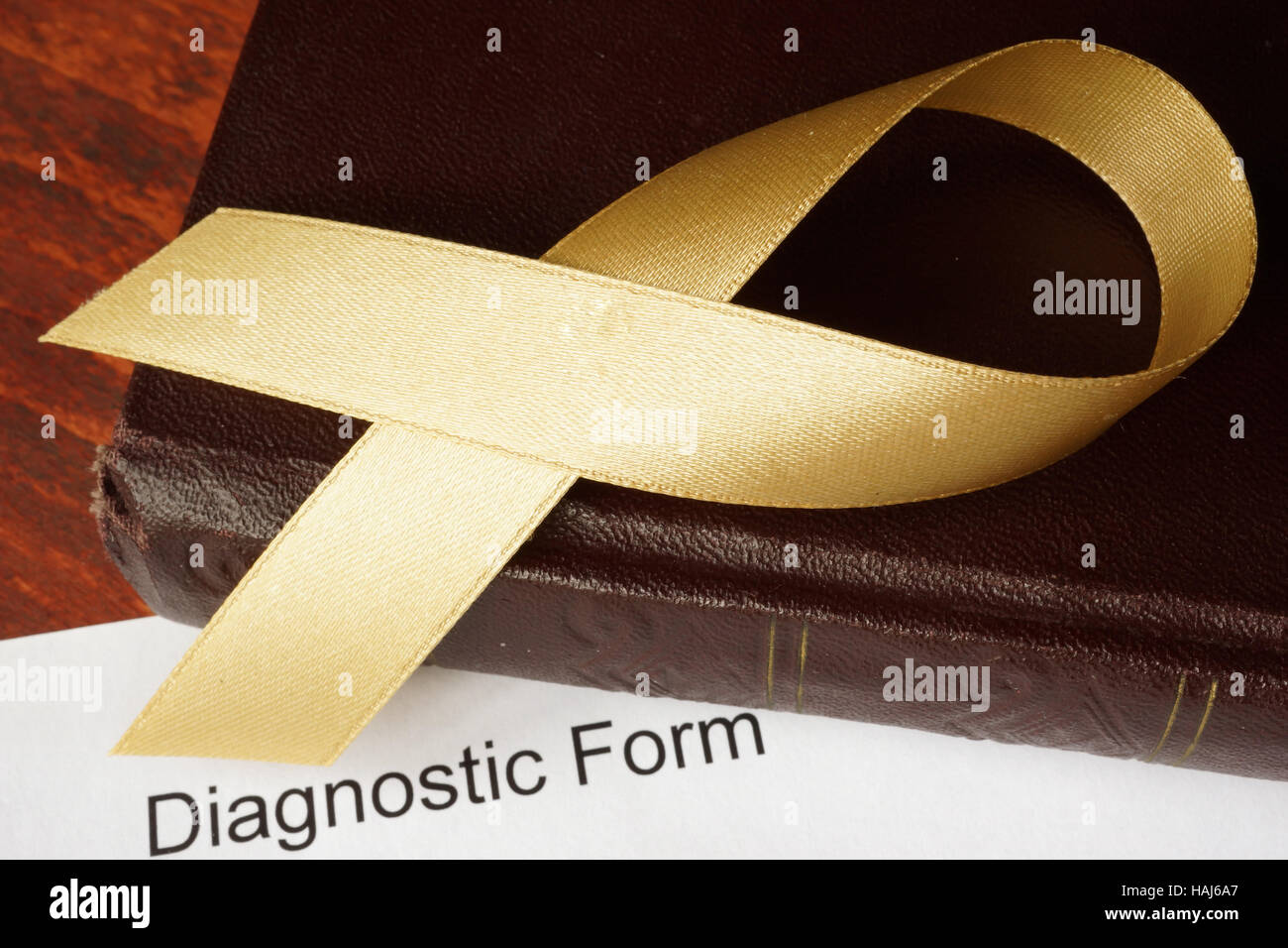 Childhood cancer diagnosis.  Gold awareness ribbon on a book. Stock Photo
