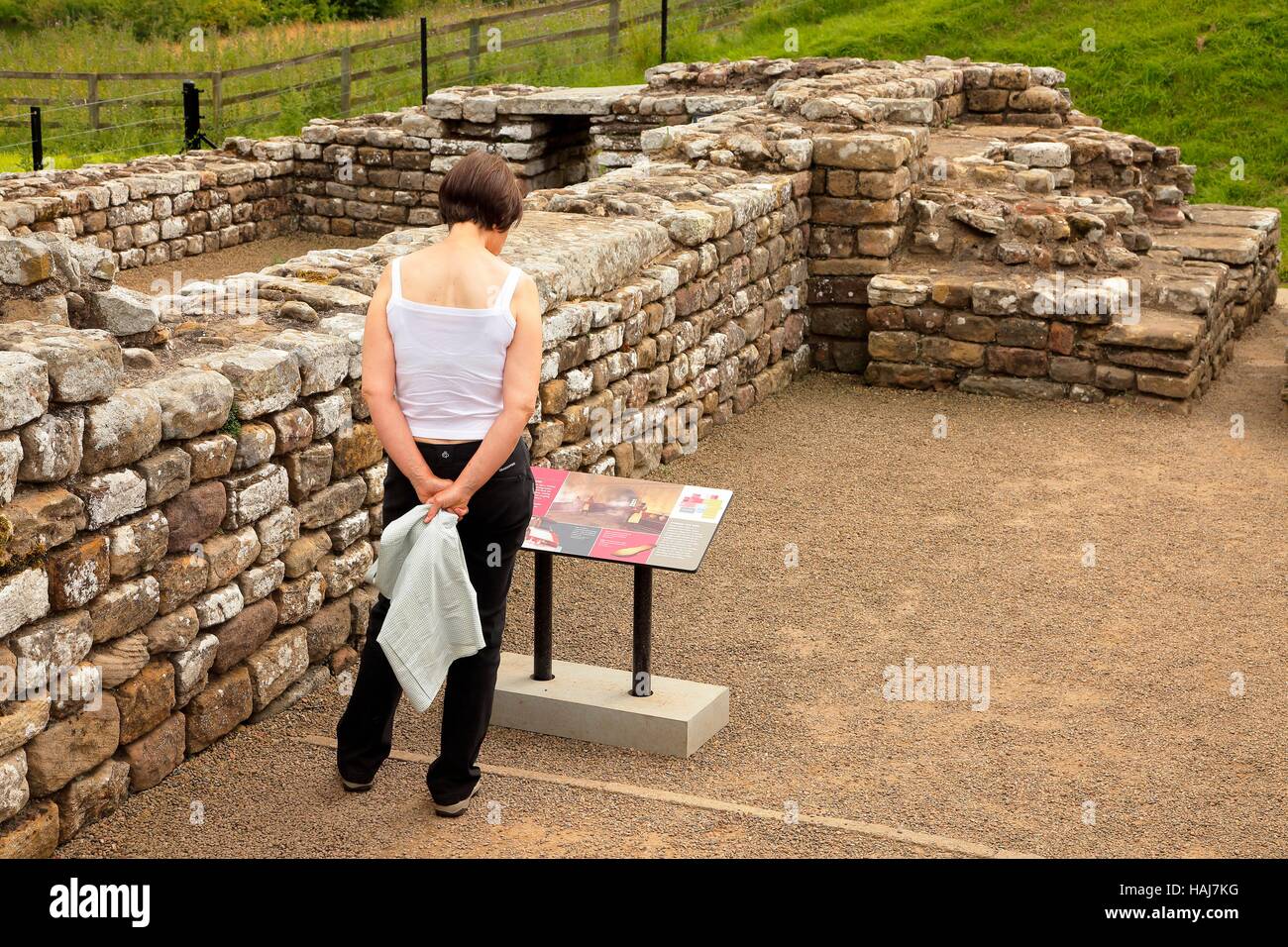Woman reading information sign. Chesters Roman Fort and Museum bathhouse. Chollerford, Hexham, Northumberland, England, United Kingdom, Europe. Stock Photo