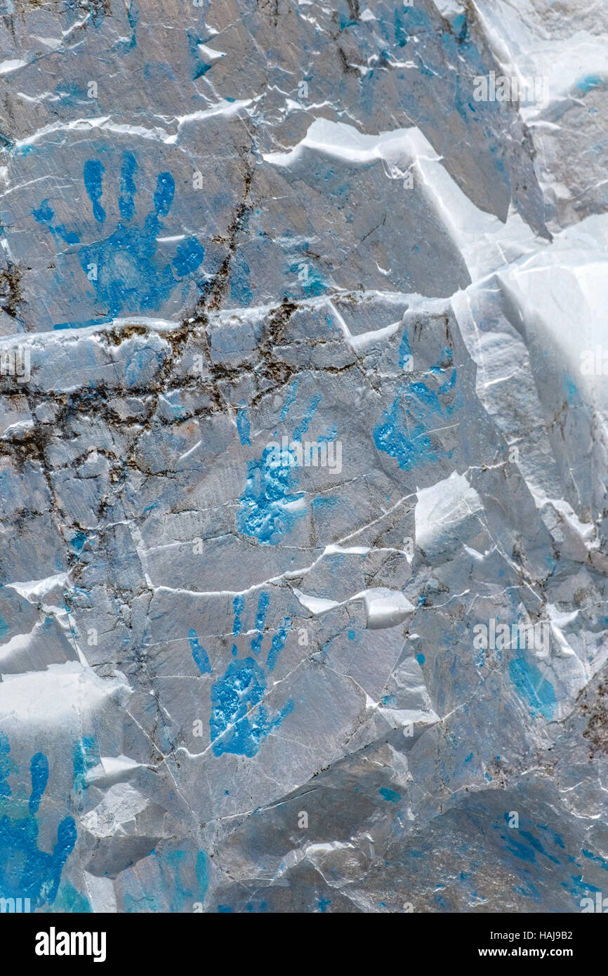 Blue hand prints on cracked metallic shining stone wall Stock Photo