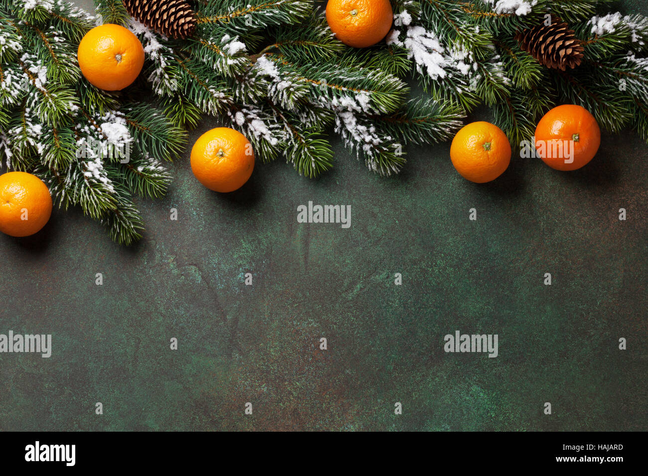 Christmas stone background with snow fir tree and tangerines. Top view ...