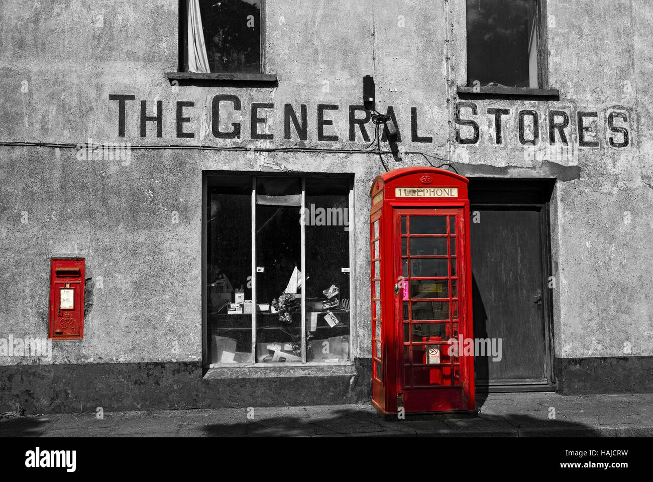 Red phone box and post box outside disused store in a black and white image, Mathry, Pembrokeshire, Wales, UK. Stock Photo