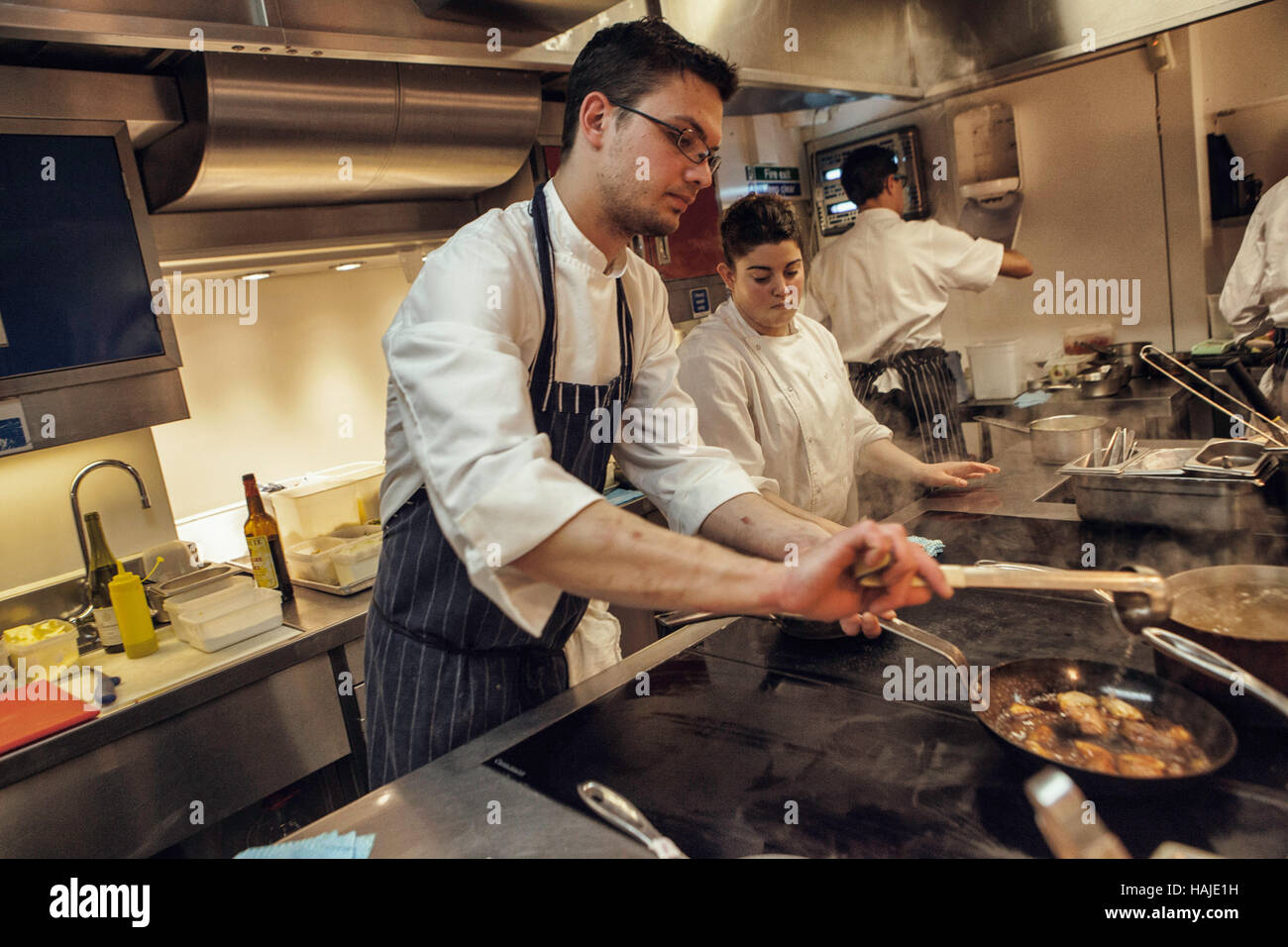 Eric Gabulya, Demi Chef de Partie,  and Alexia Dellaca-Minot, Chef de Partie, preparae a dish for lunch service. The kitchen of Gauthier Soho in Centr Stock Photo